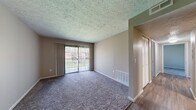 Located at 2501 Prairie Green Dr in Urbana, IL, this single-floor unit offers a practical and comfortable layout designed for everyday living. The living room serves as the central gathering space, featuring plush wall-to-wall carpeting, neutral-toned walls, and a textured ceiling. A full-width sliding glass door fitted with vertical blinds fills the room with natural light and provides outdoor views, creating an open and airy atmosphere.

The galley-style kitchen is efficiently arranged with light wood cabinetry lining both sides, offering ample storage and counter space. Light-toned laminate countertops, a stainless steel sink, and black appliances — including an electric range and refrigerator — complete the functional cooking space. Wood-look flooring runs through the kitchen and connecting hallway areas.

The bedrooms are carpeted and feature windows with horizontal blinds that bring in natural light. Closet space is available, and the rooms connect via a hardwood-style hallway. The bathroom includes a wood-toned vanity with a white countertop, a wall mirror, and a tub-shower combination, all set on wood-look flooring. The unit's straightforward layout and consistent finishes provide a clean, move-in-ready environment.