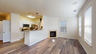 This single-floor residence offers a thoughtfully designed open-concept layout that seamlessly connects the living and kitchen areas. The living room is a standout space, featuring rich hardwood-style flooring, crown molding, and a tiled corner fireplace that serves as a warm focal point. Multiple windows dressed with white plantation shutters fill the room with natural light and contribute to the bright, airy ambiance throughout.

The kitchen is well-appointed with white shaker cabinetry, granite countertops, stainless steel appliances including a gas range, microwave, and refrigerator, and a peninsula that opens toward the living area — ideal for entertaining. Track lighting above the kitchen provides ample task illumination.

The bedrooms are carpeted for comfort, with one room featuring a ceiling fan with integrated lighting and a window with blinds allowing natural light. The bathroom includes a full soaking tub with white tile surround, offering a clean and functional space.

A dedicated in-unit laundry nook houses a full-size washer and is outfitted with overhead wire shelving for added storage. Throughout the residence, neutral tones, clean lines, and consistent flooring choices create a cohesive and inviting atmosphere well-suited for modern living.