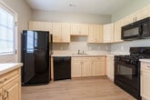 Located at 900 Barnegat Blvd N in Barnegat, New Jersey, this two-floor residence offers a practical and well-organized layout throughout its living spaces. The main level features warm hardwood flooring that extends through the living and dining areas, with neutral gray walls that create a clean, versatile backdrop. The living room benefits from natural light through a front-facing window and includes a staircase leading to the upper floor. Adjacent to the living area, a dedicated dining space is highlighted by a pendant light fixture and matching hardwood floors. The kitchen is efficiently designed in an L-shaped configuration, featuring light maple cabinetry with raised-panel doors, white countertops, a stainless steel sink, and a full suite of black appliances including a gas range, built-in microwave, dishwasher, and refrigerator. A back door with window panels provides additional natural light and exterior access. Two bathrooms serve the home, each finished with warm tile flooring, light wood vanities, white countertops, and chrome fixtures — one including a soaking tub. The upper level bedrooms are carpeted for comfort, with windows overlooking the surrounding greenery. This residence provides a functional, move-in-ready layout suited for everyday living.