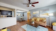 Located at 4101 W Union Hills Dr in Phoenix, AZ, this single-floor residence offers two bedrooms, two bathrooms, and three closets within a well-organized layout. The living room is warm and inviting, featuring wood-style flooring, a ceiling fan with light fixture, and a large sliding glass door with vertical blinds that allows natural light to fill the space. The dining area is tucked into a defined nook with a skylight overhead, adding a bright, airy feel to mealtimes. The galley-style kitchen is efficiently arranged with warm wood cabinetry, a full suite of black appliances including a refrigerator, range, and microwave, plus a dishwasher and a sink along the opposite counter. The primary bedroom features plush carpeting, a neutral color palette, and a closet, while the second bedroom is bright and simply appointed with carpeted flooring and a window with vertical blinds. Both bathrooms include a tub-shower combination with hardwood-style flooring. Throughout the home, consistent gray-toned walls and textured ceilings create a cohesive aesthetic, while the mix of hard flooring and carpet adds practical comfort across all living areas.