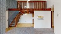 Located at 5916 Shakertown Dr NW in Canton, Ohio, this distinctive unit offers a striking architectural layout centered around a dramatic loft-style upper level. The main living area immediately draws attention with soaring vertical space, a bold wood-railed staircase and loft balustrade crafted from warm-toned timber, and a ceiling fan overhead. A pass-through window connects the living space to the kitchen, adding both functionality and visual openness to the layout.

The kitchen is efficiently designed with warm wood cabinetry, granite-patterned countertops, a double-basin sink, a refrigerator, and an electric range, all set atop tile flooring. The bedroom features plush carpeting, a ceiling fan with light fixture, a window with blinds that allows natural light in, and a baseboard heating unit. A second carpeted room, accessible via the loft level, includes vaulted ceilings, a wall-mounted air conditioning unit, a sliding glass door with vertical blinds, and access to a closet.

The full bathroom includes a wood-vanity with a large mirror, white countertop, a tub-shower combination, and tile flooring. Throughout the space, the combination of wood accents, carpet, and tile creates a warm, functional environment suited for everyday living.