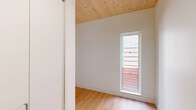Located at 517 W Main St in Madison, WI, this thoughtfully designed 3-bedroom, 2-bathroom single-floor residence showcases a clean, contemporary aesthetic throughout. Distinctive natural pine wood ceilings run across the living spaces and kitchen, lending warmth and texture to the modern interior, while light hardwood flooring unifies the layout cohesively.

The open kitchen is a standout feature, equipped with sleek matte gray cabinetry, a central island, stainless steel appliances including a full-size refrigerator, and under-cabinet lighting. Large windows along the kitchen and living area draw in generous natural light and offer views of the surrounding greenery.

The primary bedroom is a well-proportioned retreat, featuring the same wood-plank ceiling and direct access to a private balcony through floor-to-ceiling glass doors with views of outdoor foliage. The two additional bedrooms share similar bright, airy qualities with natural light filtering through windows.

The bathrooms are finished to a high standard. One features large-format neutral stone tiles, a soaking tub with shower, wall-mounted toilet, and a floating vanity with a terrazzo vessel sink. The second bath echoes this refined minimalism with matching fixtures and finishes. Two hallways connect the spaces efficiently, completing this well-appointed home.