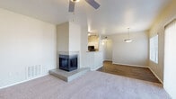 This single-floor residence offers a thoughtfully designed layout that balances comfort and functionality throughout. The living room serves as the heart of the home, anchored by a striking corner three-sided fireplace set on a raised hearth, which adds architectural character to the space. Vaulted ceilings and a ceiling fan enhance the open, airy feel, while plush carpeting adds warmth underfoot. The living area flows seamlessly into a dining area with wood-look flooring and a pendant light fixture, creating a natural transition between spaces.

The kitchen is efficiently arranged with white cabinetry, granite-look countertops, and a full suite of black appliances including a refrigerator, electric range, and over-the-range microwave. Wood-look flooring continues throughout the kitchen and connects to an adjacent utility area. The in-unit laundry room houses a full-size washer and dryer alongside a water heater and HVAC system, providing added convenience.

The bedrooms are carpeted and filled with natural light from large windows with blinds, each equipped with a ceiling fan. The bathrooms feature white vanity cabinetry with speckled countertops, wood-look tile flooring, and clean, neutral finishes. One bathroom includes a tub-shower combo with a bright window above, while the other offers a wide vanity with an expansive mirror.