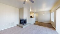 This single-floor residence offers a thoughtfully designed layout that balances comfort and functionality throughout. The living room serves as the heart of the home, anchored by a striking corner three-sided fireplace set on a raised hearth, which adds architectural character to the space. Vaulted ceilings and a ceiling fan enhance the open, airy feel, while plush carpeting adds warmth underfoot. The living area flows seamlessly into a dining area with wood-look flooring and a pendant light fixture, creating a natural transition between spaces.

The kitchen is efficiently arranged with white cabinetry, granite-look countertops, and a full suite of black appliances including a refrigerator, electric range, and over-the-range microwave. Wood-look flooring continues throughout the kitchen and connects to an adjacent utility area. The in-unit laundry room houses a full-size washer and dryer alongside a water heater and HVAC system, providing added convenience.

The bedrooms are carpeted and filled with natural light from large windows with blinds, each equipped with a ceiling fan. The bathrooms feature white vanity cabinetry with speckled countertops, wood-look tile flooring, and clean, neutral finishes. One bathroom includes a tub-shower combo with a bright window above, while the other offers a wide vanity with an expansive mirror.
