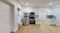 Located at 601 W Cliveden St in Philadelphia's Mt. Airy neighborhood, this single-floor 2-bedroom, 1-bathroom unit offers a clean, modern aesthetic throughout. Light wood luxury vinyl flooring runs consistently across every room, complemented by crisp white walls, white baseboards, and recessed lighting in key areas.

The entrance opens into a well-proportioned living area featuring a window with blinds and a classic cast-iron radiator. Two connecting hallways guide movement through the unit, providing efficient access to all rooms. The kitchen is a standout, outfitted with white shaker-style cabinetry, a light blue subway tile backsplash, white quartz countertops, and a full suite of stainless steel appliances including a gas range, over-the-range microwave, and refrigerator.

The spacious primary bedroom includes recessed lighting, a window for natural light, and dedicated closet access. The second bedroom features a window and a cast-iron radiator. The bathroom is finished with a geometric patterned tile accent wall, a soaking tub, dark slate floor tile, and a window for ventilation. A dedicated laundry area and additional closet storage add practical convenience to this well-appointed unit.