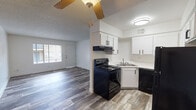 This single-floor residence offers a clean, modern interior with a thoughtful layout designed for comfortable everyday living. The open-concept living and dining area is finished with wood-look plank flooring and features a ceiling fan, a textured ceiling, and a front-facing window that allows natural light to fill the space. A front entry door opens directly into this welcoming area, creating an accessible and functional flow.

The kitchen is efficiently designed with crisp white shaker-style cabinetry, black hardware, and light-toned countertops. Black appliances — including a range, dishwasher, and refrigerator — provide a bold contrast against the white cabinetry, while a stainless steel sink and under-cabinet range hood complete the setup. The kitchen connects seamlessly to the main living area, supporting an open and sociable floor plan.

The bedrooms are carpeted for comfort and feature textured ceilings and windows that bring in natural light. The primary bedroom includes access to a walk-in closet and an en-suite bathroom. The bathroom is finished in a clean, neutral palette with a tub-shower combination, a vanity with a marble-style countertop, and a large mirror with overhead lighting. The overall aesthetic throughout the residence is fresh and move-in ready, with bright white walls and updated finishes that create a light, airy atmosphere.