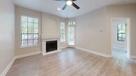This thoughtfully designed single-story residence offers a comfortable and efficient layout across one bedroom and one bathroom. Throughout the home, light-toned luxury vinyl plank flooring and warm neutral walls create a cohesive, modern aesthetic.

The living room serves as the heart of the home, featuring a classic fireplace with an arched mantel surround, a ceiling fan with recessed lighting, and multiple windows that invite generous natural light. A sliding glass door opens directly to an outdoor patio area with views of surrounding greenery, enhancing the sense of connection to the outdoors.

The kitchen is well-equipped with white shaker-style cabinetry, marble-look quartz countertops, a stainless steel double-basin sink, and a full suite of stainless steel appliances including an electric range, microwave, and dishwasher. Adjacent to the kitchen, built-in shelving with cabinetry below provides practical and stylish storage.

The bedroom is a bright, serene space highlighted by a distinctive multi-pane black-framed window that frames lush outdoor tree views. A dedicated closet and convenient laundry area add everyday functionality. The bathroom includes a full soaking tub with shower, toilet, and additional closet storage. A hallway connects all areas of the home seamlessly.