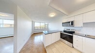 Located on the third floor at 4750 Bathurst St in Toronto's North York neighbourhood, this 1-bedroom, 1-bathroom unit offers a functional and comfortable layout. The kitchen is a standout feature, equipped with stainless steel appliances including a range, over-the-range microwave, and refrigerator. White shaker-style cabinetry, a subway tile backsplash, and dark countertops complete the clean, modern aesthetic. A peninsula provides additional counter space and separates the kitchen from the living area. Warm parquet flooring flows throughout the living spaces, adding character and continuity. The bedroom is a well-sized retreat featuring mirrored sliding closet doors and a large window with baseboard heating beneath it, offering treetop views of the surrounding neighbourhood. The living area also benefits from expansive windows that invite natural light and frame leafy outdoor views. The bathroom is finished with classic white subway tile surrounding a full bathtub and shower combination, complemented by chrome fixtures for a crisp, clean look. The overall ambiance of the unit is bright and neutral, with a practical layout well-suited for comfortable everyday living in a mature, tree-lined Toronto community.