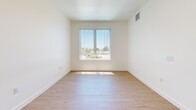 This 2-bedroom, 1-bathroom unit in National City, California offers a clean, modern layout across a single floor. Light wood flooring flows consistently throughout every room, lending warmth and visual continuity to the entire space. The living area is open and bright, benefiting from natural light that filters in through multiple windows fitted with vertical blinds.

The kitchen is efficiently designed with dark espresso-toned cabinetry that contrasts sharply against the light walls and flooring. Black appliances, including a refrigerator, dishwasher, and range, are integrated into the layout, complemented by recessed ceiling lighting that ensures clear, functional illumination. A window in the kitchen brings in additional natural light.

Both bedrooms are well-proportioned, featuring the same light wood flooring and crisp white walls. Each room is equipped with multiple windows offering outdoor views and allowing ample sunlight to enter. The primary bedroom provides a comfortable footprint with sufficient wall space for furniture placement.

The full bathroom maintains the home's clean aesthetic with white walls, wood-look flooring, and a tub-shower combination. A hallway connects the main living areas to the bedrooms and bathroom, enhancing the logical flow of the floor plan. Overall, the unit presents a bright, minimal, and move-in-ready environment.