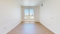 This 2-bedroom, 1-bathroom unit in National City, California offers a clean, modern layout across a single floor. Light wood flooring flows consistently throughout every room, lending warmth and visual continuity to the entire space. The living area is open and bright, benefiting from natural light that filters in through multiple windows fitted with vertical blinds.

The kitchen is efficiently designed with dark espresso-toned cabinetry that contrasts sharply against the light walls and flooring. Black appliances, including a refrigerator, dishwasher, and range, are integrated into the layout, complemented by recessed ceiling lighting that ensures clear, functional illumination. A window in the kitchen brings in additional natural light.

Both bedrooms are well-proportioned, featuring the same light wood flooring and crisp white walls. Each room is equipped with multiple windows offering outdoor views and allowing ample sunlight to enter. The primary bedroom provides a comfortable footprint with sufficient wall space for furniture placement.

The full bathroom maintains the home's clean aesthetic with white walls, wood-look flooring, and a tub-shower combination. A hallway connects the main living areas to the bedrooms and bathroom, enhancing the logical flow of the floor plan. Overall, the unit presents a bright, minimal, and move-in-ready environment.