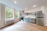 Located at 401 Union Ave SE in Olympia, Washington, this efficiently designed studio unit offers a thoughtfully arranged single-floor layout that maximizes every square foot. Light wood-look vinyl plank flooring flows throughout the entire space, creating a cohesive and contemporary aesthetic.

The open-plan kitchen and living area serves as the heart of the unit. The kitchen is well-appointed with sage-toned flat-front cabinetry, light countertops, a stainless steel refrigerator, electric range with hood, and a dishwasher. A wall-mounted HVAC unit provides climate control. Large windows along the living area wall invite generous natural light and frame lush, green tree canopy views, lending the space a bright and airy feel.

The combined bathroom and laundry room is finished in a clean, all-white palette with wood-look flooring, a full soaking tub and shower, a vanity with matching grey cabinetry, and in-unit laundry hookups — maximizing practicality within a compact footprint.

Three closets provide notable storage for a studio-sized unit, including a double sliding-door closet in the sleeping area. The unit features a neutral warm-white color scheme throughout, recessed lighting, and clean-lined Craftsman-style interior doors, all contributing to a modern yet inviting atmosphere.
