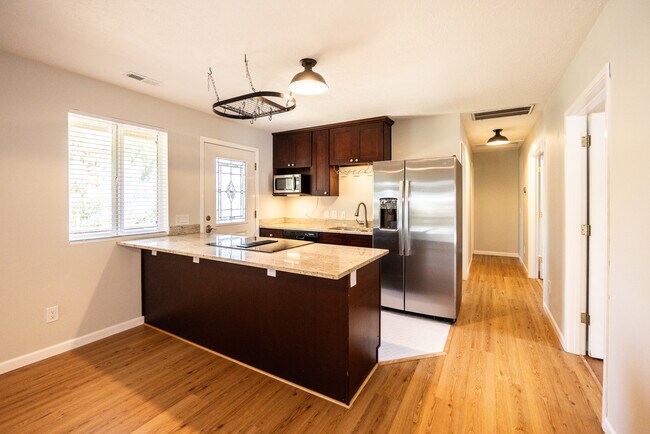 Cocina. Encimeras de granito, cajones y armarios con cierre suave, nevera nueva de acero inoxidable, suelo de baldosas cerámicas. - 8717 NE Webster St