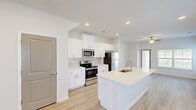 This two-story home in Augusta, Georgia offers a well-designed layout across two floors, thoughtfully balancing communal and private living spaces. The main floor opens into a bright, open-concept kitchen and living area bathed in natural light from multiple windows. The kitchen is a standout feature, showcasing crisp white shaker cabinetry, light quartz countertops, a stainless steel appliance suite including a range, microwave, and refrigerator, and a central island with a built-in sink — ideal for both meal prep and casual dining. Light wood-style flooring runs seamlessly throughout, complementing the home's clean, neutral palette. A ceiling fan in the living area adds comfort and airflow to the spacious open floor plan. The upper floor houses the two bedrooms, including a generously sized primary bedroom with multiple windows, a ceiling fan, and ample natural light. The primary suite includes a walk-in closet with wire shelving and a private en-suite bathroom featuring a glass-enclosed walk-in shower, white vanity cabinetry, and wood-look flooring. Additional bedrooms offer double-door closets and bright windows. Three full bathrooms across both floors ensure convenience for residents and guests alike.