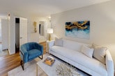 Located at 100 Stonegate Way in Middle Island, NY, this single-floor residence offers a thoughtfully designed layout with stylish, modern finishes throughout. The open-concept living area features warm hardwood-style flooring, neutral walls, and a sliding glass door that floods the space with natural light and leads to a private patio overlooking a wooded backdrop — ideal for relaxing or entertaining outdoors.

The kitchen is outfitted with dark espresso shaker-style cabinetry, gleaming quartz countertops, stainless steel appliances including a gas range, microwave, and refrigerator, as well as a double undermount sink — combining functionality with a refined aesthetic.

The bedrooms are generously sized with plush carpeting, large windows that invite natural light, and ample closet space. The primary bedroom includes a dedicated en-suite bathroom, while additional bedrooms are well-proportioned and versatile.

The bathrooms are finished with quartz vanity countertops, dark cabinetry, tile flooring, and a tub-shower combination, delivering a clean and contemporary feel. Throughout the residence, a cohesive neutral color palette creates a calm and inviting ambiance, making this a comfortable and functional home in a serene Long Island setting.