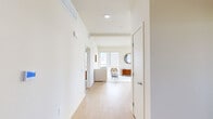 This thoughtfully designed single-floor residence in Oakland, CA offers a clean, modern aesthetic defined by crisp white walls, light wood flooring, and an open, airy layout. The interior is organized efficiently, connecting a well-appointed living room, dining area, and kitchen in a cohesive flow.

The living room receives generous natural light through large windows framing urban skyline views, creating a bright and inviting atmosphere. The kitchen is a standout feature, equipped with two-tone grey and white cabinetry, stainless steel appliances including a gas range and full-size refrigerator, white quartz countertops, a decorative tile backsplash, and a central island. The adjacent dining area benefits from expansive sliding glass doors and windows, offering sweeping outdoor views and abundant daylight.

Both bedrooms are comfortably scaled with plush carpeting and well-positioned windows that bring in natural light. The primary bedroom features a large window overlooking the surrounding neighborhood. The three bathrooms are finished with marble-patterned wall surrounds, wood-look flooring, and clean white vanities — two featuring a walk-in shower and soaking tub, respectively. A hallway closet provides additional storage throughout this well-organized residence.