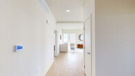This thoughtfully designed single-floor residence in Oakland, CA offers a clean, modern aesthetic defined by crisp white walls, light wood flooring, and an open, airy layout. The interior is organized efficiently, connecting a well-appointed living room, dining area, and kitchen in a cohesive flow.

The living room receives generous natural light through large windows framing urban skyline views, creating a bright and inviting atmosphere. The kitchen is a standout feature, equipped with two-tone grey and white cabinetry, stainless steel appliances including a gas range and full-size refrigerator, white quartz countertops, a decorative tile backsplash, and a central island. The adjacent dining area benefits from expansive sliding glass doors and windows, offering sweeping outdoor views and abundant daylight.

Both bedrooms are comfortably scaled with plush carpeting and well-positioned windows that bring in natural light. The primary bedroom features a large window overlooking the surrounding neighborhood. The three bathrooms are finished with marble-patterned wall surrounds, wood-look flooring, and clean white vanities — two featuring a walk-in shower and soaking tub, respectively. A hallway closet provides additional storage throughout this well-organized residence.