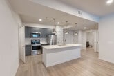 Located in Atlanta's vibrant Old Fourth Ward neighborhood, this well-appointed 2-bedroom, 4-bathroom residence offers a thoughtfully designed single-level layout. The open-concept kitchen and living area serves as the heart of the home, anchored by a generous island with quartz countertops, an undermount sink, and a trio of brushed nickel pendant lights overhead. Dark charcoal cabinetry contrasts beautifully with the white surfaces, while a full suite of stainless steel appliances — including a gas range, microwave, refrigerator, and dishwasher — completes the modern kitchen. Light wood-style flooring flows seamlessly throughout the living areas, complementing the neutral white walls and creating a bright, airy atmosphere. The living room benefits from multiple windows that invite natural light and feature a ceiling fan for year-round comfort. Each bedroom is well-proportioned, with the primary bedroom offering its own dedicated closet space equipped with built-in shelving and hanging rods. The bathrooms are finished with dark cabinetry, quartz vanity countertops, large mirrors, and stylish sconce lighting. A dedicated laundry room with in-unit washer and dryer adds everyday convenience, rounding out this clean, contemporary residence.