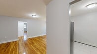 Located at 1059 Pompton Ave in Cedar Grove, NJ, this one-bedroom, one-bathroom unit offers a well-organized, single-floor layout with a clean, neutral aesthetic throughout. Gleaming hardwood floors run through the living room, bedroom, and hallways, lending warmth and continuity to the space.

The combined kitchen and living area provides a practical, open feel. The kitchen is outfitted with crisp white shaker-style cabinetry, light countertops, a stainless steel dishwasher, gas range, and microwave — all set atop light tile flooring that complements the overall bright palette.

The spacious living room features soft gray walls, polished hardwood floors, and a large multi-pane window that allows generous natural light and views of the surrounding greenery. A wall-mounted air conditioning unit ensures year-round comfort.

The primary bedroom is a comfortable, well-proportioned room with hardwood floors, a window overlooking the outdoors, and baseboard heating supplemented by a wall A/C unit. Additional rooms provide flexible hallway and storage space connecting the main areas.

The bathroom is finished in all-white tile with a full soaking tub and shower combination, chrome fixtures, and a frosted window that provides both light and privacy. Two hallways connect the rooms efficiently, rounding out this tidy and functional Cedar Grove residence.