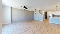 This well-appointed two-story home in Princeton, TX offers 3 bedrooms and 4 bathrooms across two thoughtfully designed floors. The main level features an open-concept kitchen and living area with light hardwood-style flooring throughout. The kitchen is outfitted with crisp white shaker cabinetry, quartz countertops, a central island, stainless steel appliances, and a soft blue subway tile backsplash. The living room showcases a striking board-and-batten accent wall in a warm gray tone, a ceiling fan with built-in lighting, a pendant light fixture, and a staircase leading to the upper level. An attached garage with a roll-up door and a dedicated laundry area with hookups round out the main floor. Upstairs, the generously sized primary bedroom features plush carpet, a ceiling fan, and access to a spacious walk-in closet with built-in shelving and hanging rods. The additional bedrooms are carpeted and include ceiling fans and dark-accented doors with closets. The four bathrooms are finished with patterned tile flooring, white subway tile walk-in showers with frameless glass enclosures, white vanities with quartz countertops, and matte black hardware throughout, creating a cohesive modern aesthetic.