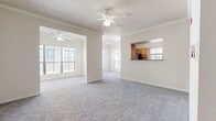 This single-floor residence offers a thoughtfully designed layout that balances open living spaces with functional private areas. The main living and dining areas are generously proportioned, featuring neutral-toned carpet, crown molding, and ceiling fans that contribute to a clean, comfortable ambiance. Multiple large windows flood the space with natural light, enhancing the bright, airy feel throughout.

The kitchen is equipped with warm oak cabinetry, dark granite-style countertops, and black appliances including an electric range, over-the-range microwave, and dishwasher, all set atop hardwood flooring. A pass-through window connects the kitchen to the living area, promoting an open, communicative flow between spaces. Track lighting in the dining area adds a practical and modern touch.

A dedicated dining nook sits adjacent to the living room, defined by its own ceiling fan and window. The bedrooms are carpeted and receive natural light through window-blind-fitted windows. The primary bedroom benefits from a spacious walk-in closet outfitted with wire shelving and hanging rods on three walls, providing ample storage.

The bathroom features a full soaking tub with tiled surround in white and taupe accents, complemented by hardwood flooring. A separate laundry area includes washer/dryer hookups, wire shelving overhead, and tile flooring, adding everyday convenience to this well-rounded residence.