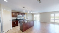 Located at 3103 E Calgary Ave in Bismarck, North Dakota, this well-appointed 3-bedroom, 2-bathroom single-floor unit offers a functional and modern layout across a comfortable footprint. The heart of the home is an open-concept kitchen and living area, where rich dark-stained cabinetry pairs with dark granite countertops and a full suite of stainless steel appliances, including a gas range, microwave, and refrigerator. A central kitchen island with an undermount sink adds workspace and visual appeal, while pendant lighting overhead enhances the contemporary aesthetic. Light hardwood-style flooring flows throughout the main living areas, complementing the neutral warm-toned walls. The living space benefits from a sliding glass door that invites natural light and provides outdoor access. The three bedrooms feature plush carpet flooring and windows with exterior views. The primary bedroom connects to a private bathroom with a walk-in shower and a dark-vanity with granite countertop. The second bathroom offers a full tub-shower combination with matching finishes. Additional highlights include a dedicated laundry room, a pantry, four closets for generous storage, and a hallway connecting the unit's well-organized layout. The overall ambiance is clean, modern, and move-in ready.