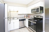 This single-floor residence offers a thoughtfully designed layout with functional spaces throughout. The kitchen is outfitted with white shaker-style cabinetry, granite-style countertops, and a full suite of stainless steel appliances, including a refrigerator, dishwasher, range, and microwave. Light wood-style flooring ties the kitchen together, giving it a clean and contemporary feel.

The living area is generously sized, featuring plush carpeting, neutral taupe walls, and a textured ceiling. A ceiling fan adds comfort, while a large sliding glass door opens directly onto a private balcony, allowing for abundant natural light and outdoor access. An additional window further brightens the space.

The bedrooms are carpeted and finished with the same warm neutral tones, each offering windows that bring in natural light. One bedroom includes a wall-mounted utility panel near the entry door.

The unit includes two bathrooms. The first features a tub-shower combination, a toilet, and overhead cabinetry for storage. The second is a well-organized full bath with a glass-enclosed walk-in shower, granite-topped vanity, and additional overhead white cabinetry. Both bathrooms are finished with light wood-style flooring and warm neutral walls, creating a cohesive and comfortable atmosphere throughout the home.