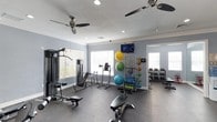 Located at 2850 Courtney Creek Blvd in Durham, NC, this fitness center offers a well-appointed, single-floor workout facility designed to support a wide range of exercise routines. The space is bright and airy, thanks to multiple windows fitted with blinds that allow natural light to fill the room while maintaining privacy. Two ceiling fans keep the environment comfortable during workouts, complemented by recessed lighting overhead.

The gym floor is covered in durable rubber flooring, ideal for both heavy equipment and high-impact exercises. Strength training is well represented with a cable resistance machine, adjustable benches, and a dedicated dumbbell rack stocked with a full range of weights. Functional fitness enthusiasts will appreciate the stability ball rack, resistance bands, and medicine balls available for dynamic training.

A wall-mounted flat-screen television adds entertainment options for those looking to stay engaged during longer sessions. Crown molding along the ceiling gives the space a polished, finished look that elevates the overall aesthetic. With ample floor space, natural light, and a diverse selection of equipment, this fitness center provides a comprehensive and inviting environment for residents to pursue their health and wellness goals.