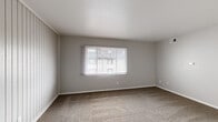Located at 4333 Chesford Rd in Columbus, Ohio, this single-floor, one-bedroom, one-bathroom home offers a practical and comfortable layout with consistent neutral finishes throughout. The living room is a welcoming space featuring plush carpeting, soft gray walls, and a distinctive vertical-panel accent wall that adds texture and character. A large window allows natural light to fill the room, creating a bright and open atmosphere. The living area also features ceiling-mounted HVAC vents, ensuring year-round climate comfort. The bedroom is generously sized, offering ample room for furnishings, and is outfitted with the same warm carpeting found throughout the home. A window provides natural light and outdoor views, while a sliding-door closet with a hanging rod offers practical storage. An additional carpeted room provides flexible space that can serve as a secondary living area or office. The full bathroom is clean and functional, featuring a white tub and shower combination with tiled surround, a vanity with dark cabinetry, and a round mirror. The home's consistent use of neutral gray tones, white trim, and soft carpeting throughout creates a cohesive, understated aesthetic that is easy to personalize.