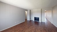Located at 9100 Duarte Rd in San Gabriel, California, this single-floor unit offers a practical and comfortable layout designed for everyday living. The living area serves as the heart of the space, featuring rich dark hardwood-style flooring, neutral gray walls, and a textured ceiling. A built-in fireplace anchors one wall, providing both a functional heating element and a focal point for the room. Natural light filters in through large windows fitted with vertical blinds throughout the unit.

The galley-style kitchen is well-appointed with white upper cabinetry extending to the ceiling for ample storage, contrasting dark lower cabinets, and sleek quartz countertops. A stainless steel refrigerator and a dedicated pantry closet add to the kitchen's practicality. The layout flows efficiently, connecting seamlessly to the rest of the unit.

The bedrooms are carpeted for comfort and include large windows with vertical blinds, allowing for natural light and ventilation. Wall-mounted air conditioning units provide climate control in the sleeping areas. The bathroom includes a white vanity with cabinet storage, a mirrored medicine cabinet, and a clean, bright tub and shower combination, all finished in neutral tones that contribute to the unit's cohesive aesthetic.