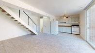 This two-story home in Ypsilanti, Michigan offers three bedrooms and one and a half bathrooms across a comfortably sized layout. The main level features an open-concept design where the living area flows directly into the kitchen. The living space is carpeted and benefits from natural light via a sliding glass door that opens to an outdoor area. A staircase with a metal railing connects the main level to the upper floor. The kitchen is equipped with white cabinetry, granite-style laminate countertops, a stainless steel sink, a white refrigerator, and a white range. Tile flooring runs through the kitchen, which also connects to a convenient half bath nearby. Upstairs, the carpeted bedrooms are well-proportioned, each featuring bifold-door closets with built-in rods and shelving. Several bedrooms include sliding glass doors or windows that invite natural light. The full bathroom on the upper level includes a tub-shower combination, a pedestal sink, tile flooring, and brushed nickel fixtures. A ceiling fan in the main living area adds to the functional comfort of this straightforward, move-in-ready home.