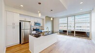 Located at 25 Garfield Pl in Cincinnati's vibrant urban core, this one-bedroom, one-bathroom residence offers a well-designed layout with modern finishes throughout. The open-concept kitchen and living area serves as the heart of the unit, featuring white shaker cabinetry, a subway tile backsplash, stainless steel appliances including a refrigerator, microwave, and range, and a central island with striking dark granite countertops and an undermount sink with a brushed gold faucet. Pendant lighting above the island adds a contemporary touch, while large floor-to-ceiling windows flood the space with natural light and frame sweeping city views of the Cincinnati skyline. Light-toned hardwood flooring runs throughout the unit, lending warmth and continuity to every room. The bedroom is a comfortable, sun-filled retreat with its own oversized window offering additional urban views and a ceiling fan for added comfort. Three closets provide generous storage. The bathroom is finished with large-format white tile in a clean, minimalist walk-in shower. A connecting hallway ties the layout together efficiently. With its modern design, abundant natural light, and downtown Cincinnati location, this residence offers a polished urban living experience.