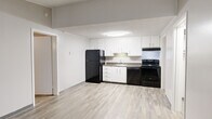 Located at 2900 Reidville Rd in Spartanburg, SC, this single-floor, two-bedroom, two-bathroom residence offers a practical and well-organized layout. The kitchen is outfitted with white cabinetry, dark granite-style countertops, a full suite of black appliances including a refrigerator, electric range, and dishwasher, all set over light wood-look flooring that extends throughout the unit. The living room provides a comfortable open space with a ceiling fan overhead and a window that allows natural light to filter in. Both bedrooms feature the same durable wood-look flooring, ceiling fans, and neutral gray walls, with the primary bedroom offering a generous footprint. Each bathroom includes white vanity cabinetry and a granite-style countertop, with one bathroom accompanied by a dedicated closet with open shelving for added storage. A dedicated laundry room houses a full-size washer and dryer, adding everyday convenience. Textured ceilings are present throughout, contributing to the unit's classic character. The consistent neutral color palette and cohesive flooring create a clean, uniform aesthetic across all rooms, making this a straightforward and functional living space.