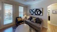 This single-floor residence offers a thoughtfully designed layout that balances comfort and functionality across its multiple rooms. The living area features warm hardwood-style flooring, crown molding, and a prominent arched built-in shelving unit that connects seamlessly to the kitchen and dining spaces. Natural light filters through window treatments, complementing the neutral tones of the walls and furnishings.

The kitchen is outfitted with dark cabinetry, granite countertops, stainless steel appliances, and a peninsula with bar seating. An in-unit washer and dryer are conveniently tucked into a dedicated laundry closet nearby. A cozy dining nook features a round wood table surrounded by upholstered chairs and an arched mirror, adding depth to the intimate space.

Both bedrooms are carpeted and feature distinct accent walls—one in a deep burgundy and one in a calming steel blue—each with a closet. The two bathrooms are finished with tile flooring, dark espresso vanities, granite countertops, and large mirrors. One bathroom includes a walk-in shower, while the other connects directly to a bedroom. Ceiling fans are present throughout for added comfort.