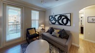 This single-floor residence offers a thoughtfully designed layout that balances comfort and functionality across its multiple rooms. The living area features warm hardwood-style flooring, crown molding, and a prominent arched built-in shelving unit that connects seamlessly to the kitchen and dining spaces. Natural light filters through window treatments, complementing the neutral tones of the walls and furnishings.

The kitchen is outfitted with dark cabinetry, granite countertops, stainless steel appliances, and a peninsula with bar seating. An in-unit washer and dryer are conveniently tucked into a dedicated laundry closet nearby. A cozy dining nook features a round wood table surrounded by upholstered chairs and an arched mirror, adding depth to the intimate space.

Both bedrooms are carpeted and feature distinct accent walls—one in a deep burgundy and one in a calming steel blue—each with a closet. The two bathrooms are finished with tile flooring, dark espresso vanities, granite countertops, and large mirrors. One bathroom includes a walk-in shower, while the other connects directly to a bedroom. Ceiling fans are present throughout for added comfort.