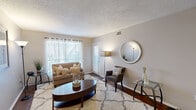 This single-story, one-bedroom, one-bathroom unit offers a thoughtfully organized layout across a compact yet efficient floor plan. The living room serves as the heart of the home, featuring rich hardwood flooring, a textured ceiling, and a large window with blinds that allows abundant natural light to fill the space. A welcoming entry area with neutral-toned walls transitions seamlessly into the living area, creating an open and airy atmosphere.

The kitchen is equipped with dark cabinetry, granite-style countertops, black appliances including a refrigerator and electric range, and hardwood flooring, providing a functional and stylish cooking space. A hallway connects the main living areas to the more private portions of the unit.

The bedroom offers comfortable carpeted flooring, a textured ceiling with a ceiling light fixture, and a sliding glass door that opens to an outdoor balcony, bringing in natural light and outdoor views. A dedicated closet provides convenient storage directly off the bedroom.

The bathroom features a wide vanity with a stone-finish countertop, a large mirror, and a shower-tub combination, finished in a clean, neutral palette. Throughout the unit, warm beige tones and consistent finishes create a cohesive and inviting ambiance.