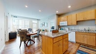 Located at 11001 Bren Rd E in Minnetonka, MN, this single-floor residence offers a thoughtfully designed open-concept layout across two bedrooms and two bathrooms. The kitchen is a standout feature, showcasing warm maple cabinetry, granite countertops, a central island with bar seating, hardwood flooring, and full appliances — all seamlessly connected to a dining area and living room. The living room is bright and inviting, benefiting from large windows with vertical blinds that allow generous natural light, a glazed door providing outdoor access, and rich hardwood floors throughout. The primary bedroom is a comfortable retreat with plush carpeting, a large window, and a dedicated closet. The second bedroom, also carpeted, offers versatile space suitable as a guest room or home office. Both bathrooms are finished with warm wood vanities, white countertops, and hardwood-style flooring. Additional highlights include a dedicated laundry area, two closets — one of which features a built-in wire shelving system — and recessed lighting throughout. The open floor plan and consistent finishes create a cohesive, functional living environment well-suited for everyday comfort.