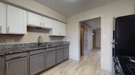 Located at 1142–1168 Druid Rd E in Clearwater, Florida, this two-floor residence offers a well-maintained interior with a cohesive, updated aesthetic throughout. Light-toned wood-look flooring runs consistently across the living areas and bedrooms, contributing to a clean, contemporary feel.

The kitchen is a standout feature, showcasing two-tone cabinetry with white upper cabinets and gray lower cabinets, dark granite countertops with subtle veining, and a modern matte-black faucet at the sink. Stainless steel appliances, including a refrigerator, gas range, and microwave, complete the functional workspace. A window above the kitchen area brings in natural light and outdoor views.

The living and bedroom spaces feature textured walls with a stucco-like finish, ceiling fans with integrated lighting, and windows fitted with blinds that allow ample natural light. The rooms offer a neutral palette that complements a variety of décor styles.

The bathroom includes a full tub-shower combination with white subway tile surround and chrome fixtures, paired with wood-look tile flooring. An in-unit laundry closet tucked beneath the staircase provides added convenience, fitted with shelving and a front-loading washer. The overall ambiance is bright, functional, and move-in ready.