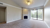 This single-floor residence offers a thoughtfully designed layout that balances comfort and functionality throughout. The spacious living room serves as the heart of the home, anchored by a classic corner fireplace with a white surround and complemented by plush wall-to-wall carpeting, crown molding, and a ceiling fan overhead. Sliding glass doors open directly to a private balcony, framing lush outdoor views and allowing natural light to fill the room generously.

The kitchen is well-equipped with rich dark cabinetry, granite countertops, a double-basin stainless steel sink, and hardwood flooring. A breakfast bar with a granite ledge connects the kitchen to the adjacent living area, creating an open and sociable flow. Stainless steel appliances complete the kitchen's polished look.

The bedrooms are carpeted and bright, with large windows—including one with a distinctive arched top—that invite ample daylight. Each room offers a calm, neutral palette and generous proportions suited for versatile use.

The bathroom features dual sinks set in a granite vanity with dark wood cabinetry, a large mirror, and a soaking tub with white tile surround accented by a row of dark decorative tiles. A walk-in closet is accessible directly from the bathroom, adding practical storage to the space.