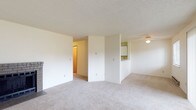 This single-floor residence offers a clean, functional layout with a comfortable and neutral aesthetic throughout. The spacious living room serves as the heart of the home, anchored by a classic brick fireplace that adds warmth and character. Soft, wall-to-wall carpeting extends across the living area and into the bedrooms, contributing to a cozy ambiance. A pass-through opening connects the living space to the kitchen, enhancing the open feel of the common areas. The kitchen is equipped with white cabinetry featuring dark trim, ample counter space, an electric range with overhead ventilation, and a built-in microwave above the stove — providing a practical and efficient cooking environment. The bedrooms are generously sized, each featuring plush carpeting, baseboard heating, and windows fitted with blinds that allow for natural light and exterior views. Ceiling fans in the bedrooms offer additional climate comfort. The full bathroom includes a tub-shower combination, a white vanity with storage, and tile flooring that adds a durable and clean finish. Textured ceilings are consistent throughout the space. Overall, the residence presents a straightforward, move-in-ready layout well-suited for comfortable everyday living.