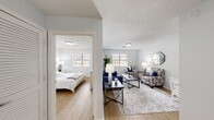 This single-floor unit offers a clean, functional layout designed with comfort and accessibility in mind. The living area serves as the heart of the space, featuring warm wood-look flooring, a textured ceiling, and multiple windows that allow natural light to fill the room. The open arrangement accommodates a seating area with ample space for relaxing or entertaining, and a small dining area is tucked neatly to one side.

The kitchen is efficiently designed with white shaker-style cabinetry, granite-look countertops, a stainless steel sink, and stainless steel appliances including an electric range and refrigerator. The layout maximizes function within a compact footprint.

The bedroom is a calm, well-lit retreat with wood-look flooring, natural light from a window with blinds, and a louvered closet door providing convenient storage. The room's neutral palette and understated design contribute to a restful ambiance.

The bathroom is equipped with an accessible tub-shower combination outfitted with sturdy grab bars and a handheld showerhead, emphasizing safety and ease of use. Throughout the unit, soft gray walls and consistent flooring create a cohesive, modern aesthetic.