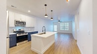 Located at 5855 S Elk Way in Aurora, CO, this thoughtfully designed single-floor residence offers 1 bedroom and 2 bathrooms within a well-utilized, efficient footprint. The open-concept living and kitchen area serves as the heart of the home, featuring warm luxury vinyl plank flooring, recessed lighting, and a ceiling fan. The kitchen is a standout, boasting a striking two-tone design with bold navy lower cabinets, crisp white upper cabinetry with gold hardware, a large hexagonal tile backsplash, white quartz countertops, stainless steel appliances, and a center island with a deep sink and stylish pendant lighting overhead. The living area extends toward large windows and a glass door, filling the space with abundant natural light. The bedroom is a comfortable retreat with a ceiling fan, a sizable window with blinds, and warm wood-look flooring. The bathrooms are tastefully finished, one featuring a navy vanity, illuminated LED mirror, and full-height gray tile accent wall. A dedicated laundry room with a full-size washer and dryer adds practical convenience. Clean white walls and consistent flooring throughout create a cohesive, modern aesthetic.