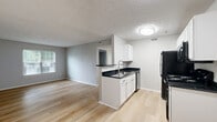 Located at 4955 Enclave Blvd in Columbus, Ohio, this two-bedroom, one-bathroom single-floor unit offers a practical and well-organized layout. The combined kitchen and living area serves as the heart of the home, featuring light wood-style flooring, neutral gray walls, and a textured ceiling. The kitchen is equipped with white shaker-style cabinetry, dark granite-style countertops, black appliances including a range, microwave, refrigerator, and dishwasher, as well as a peninsula that provides additional counter space and separation from the living area. Natural light filters into the living space through a window fitted with blinds. The primary bedroom is a comfortable size, finished with soft carpet and a window that brings in outdoor views and natural light. The second bedroom also features light wood-style flooring, neutral walls, and a textured ceiling, offering flexibility as a guest room or home office. The bathroom includes a full tub and shower combination with a curved curtain rod, wood-style flooring, and clean, simple finishes. Throughout the unit, the consistent use of neutral tones and updated flooring creates a cohesive and move-in-ready aesthetic.