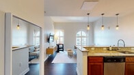 Located at 699 N Broad St in Philadelphia's vibrant Northern Liberties neighborhood, this one-bedroom, one-bathroom residence offers a thoughtfully designed layout across a single floor. The open-concept living and kitchen area is anchored by a granite-topped breakfast bar with pendant lighting overhead, complemented by rich cherry wood cabinetry, stainless steel appliances, and hardwood-style flooring. The living room is a standout, featuring soaring ceilings and striking arched windows that flood the space with natural light and offer views of the surrounding cityscape. The bedroom is a serene retreat with plush carpet, ample closet space, and charming arched and oval windows that frame city views. Three total closets provide generous storage throughout the unit. A full bathroom, dedicated laundry area, and a well-proportioned kitchen with full-length counters on both sides round out the functional layout. The neutral color palette and architectural window details lend the space a distinctive character that balances modern finishes with classic design elements.