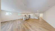 Located in Wake Forest, NC, this two-story home offers four bedrooms, four bathrooms, and a well-designed layout spread across two floors. The main floor presents an expansive open-concept living and kitchen area bathed in natural light from multiple windows. The kitchen is a standout feature, showcasing crisp white shaker cabinets, stainless steel appliances, a large center island with a built-in sink and seating, and elegant pendant lighting — all complemented by light hardwood flooring that flows seamlessly throughout the main level. The generous living room connects directly to the kitchen, creating an ideal space for entertaining. A clean, minimalist half bathroom is also located on the main floor, along with convenient garage access. The upper floor hosts all four bedrooms, including a spacious primary suite, along with the remaining bathrooms and a dedicated laundry room equipped with a full-size washer and dryer. Each bedroom features hardwood-style flooring, neutral tones, and windows with exterior views. Four closets provide ample storage throughout. The home's clean, modern aesthetic — defined by bright white walls, recessed lighting, and consistent finishes — creates a cohesive and welcoming atmosphere throughout.