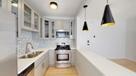 Located at 1026 Sanborn Ave in the vibrant East Hollywood neighborhood of Los Angeles, this single-floor residence offers a thoughtfully designed layout with clean, modern finishes throughout. Light hardwood flooring runs continuously across the living and kitchen areas, lending warmth and visual continuity to the space.

The kitchen is a standout feature, outfitted with gray shaker-style cabinetry — including glass-front upper cabinets — a mosaic tile backsplash, and a full suite of stainless steel appliances including a gas range, built-in microwave, dishwasher, and French door refrigerator. A white peninsula counter provides additional prep space and opens toward the living area, which is illuminated by stylish black cone pendant lights and a ceiling fan with integrated lighting.

The bedroom is bright and airy, benefiting from natural light through double windows with blinds, crown molding, a ceiling fan, and direct access to the bathroom. A spacious walk-in closet with built-in shelving offers generous storage. The bathroom is elegantly finished with white subway tile, a decorative blue mosaic accent band, black hexagon floor tile, and matte black fixtures, creating a crisp, contemporary aesthetic throughout.