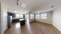 This single-floor home offers a thoughtfully designed open-concept layout that seamlessly connects the kitchen, dining, and living areas. Rich hardwood-style flooring runs throughout the main living space, complemented by a textured ceiling and a ceiling fan that adds comfort to the room. Large windows fitted with horizontal blinds fill the area with natural light and offer pleasant outdoor views.

The kitchen is a standout feature, showcasing dark espresso cabinetry that extends to the ceiling for generous storage, granite countertops, a central island with bar seating, stainless steel appliances including a refrigerator, range, and over-the-range microwave, and pendant lighting overhead. A door from the kitchen area provides convenient access to an outdoor space.

The bedrooms are carpeted and well-proportioned, each equipped with ceiling fans and windows that invite natural light. The primary bedroom connects to a private bathroom featuring granite countertops, dark cabinetry, tile flooring, and a walk-in closet with built-in shelving and hanging rods. A secondary bathroom mirrors the same granite and cabinetry finishes, with a tub-shower combination and tile flooring. A hardwood-floored hallway with additional windows connects the rooms, completing this clean and functional home.