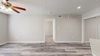 This efficiently designed 1-bedroom, 1-bathroom unit offers a thoughtful layout across a single floor. The open living area features light gray hardwood-style flooring, neutral walls, and a ceiling fan, creating a clean and inviting atmosphere. HVAC vents are strategically placed throughout, ensuring year-round comfort. The kitchen is a standout feature, equipped with white shaker-style cabinetry, white quartz countertops, a subway tile backsplash, and stainless steel appliances including a refrigerator, range, and microwave. A peninsula with a built-in sink adds additional prep space and a natural transition to the living area. The bedroom is a comfortable, carpeted retreat featuring a ceiling fan with a light fixture, a window dressed with white blinds that allows for natural light, and direct access to a closet and the bathroom. The bathroom is finished with white cabinetry, a quartz vanity top, and a tiled shower-tub combination featuring classic white subway tile accented by warm beige border tiles. Wood-style flooring in the bathroom complements the overall aesthetic of the unit, tying together a cohesive, modern design throughout the space.