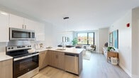 Located at 1257 West Roosevelt Road in Chicago, IL, this well-designed one-bedroom, one-bathroom unit offers a thoughtfully efficient layout with modern finishes throughout. The open-concept living and kitchen area serves as the heart of the unit, where light wood-toned flooring flows seamlessly from room to room. The kitchen is outfitted with a two-tone cabinetry scheme — white upper cabinets paired with warm wood lower cabinets — complemented by white quartz countertops, stainless steel appliances including a refrigerator, range, microwave, and dishwasher, and a sleek peninsula with a built-in sink that opens directly to the living space. A linear pendant light anchors the kitchen area with a contemporary touch. The living room is bright and airy, benefiting from large black-framed windows that invite abundant natural light and offer views of the surrounding neighborhood. The bedroom is a comfortable retreat featuring its own oversized window with outdoor views, light wood flooring, and a built-in closet with sliding doors. The bathroom is clean and functional, finished with a full tub-shower combination and neutral tiling. Throughout the unit, the consistent use of soft neutral tones and natural light creates a calm, modern ambiance ideal for urban living.