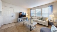 This single-floor residence offers a thoughtfully designed layout that balances comfort and functionality throughout. The living room serves as the heart of the home, featuring plush carpet flooring, large windows with blinds that invite an abundance of natural light, and ample space for seating and entertainment. Adjacent to the living area is a cozy sitting nook with French doors, providing access to the outdoors and an intimate spot ideal for casual dining or relaxation.

The kitchen is efficiently arranged in an L-shaped configuration, outfitted with warm wood-trimmed cabinetry, white panel cabinet fronts, light countertops, and wood-look vinyl flooring. It includes a full suite of appliances, including an electric range, over-the-range microwave, and dishwasher.

The bedroom is generously sized, carpeted for comfort, and features a large window that fills the room with natural light. It is complemented by a spacious walk-in closet with wire shelving systems offering excellent storage capacity. The full bathroom connects conveniently to the bedroom and features wood-look vinyl flooring, warm wood-toned cabinetry, a single vanity, and a tub-shower combination. A dedicated in-unit laundry area with washer and dryer hookups completes this well-rounded residence.