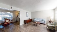 Located at 5555 Spring Valley Rd in Dallas, Texas, this single-floor residence offers a thoughtfully designed layout that balances comfort and functionality. The spacious living room is anchored by warm wood-look flooring, neutral walls, and a textured ceiling, creating a welcoming atmosphere with room to relax and entertain. An open passageway connects the living area to the rest of the home, enhancing the sense of flow throughout.

The dining area benefits from large windows that invite natural light, complemented by a classic pendant light fixture overhead and rich hardwood-style flooring underfoot. Adjacent to the dining space, the kitchen features gray cabinetry, a mosaic tile backsplash, light countertops, and a double-basin sink — offering a practical and stylish cooking environment.

The bedrooms are carpeted for added comfort, with one featuring a ceiling fan with integrated lighting and ample space for furnishings. A walk-in closet is accessible from one of the bedrooms, providing generous storage. The bathrooms are finished with updated vanities featuring speckled countertops and wood-look flooring, with shower/tub combinations enclosed by decorative curtains. Overall, the residence presents a clean, move-in ready environment in a convenient Dallas location.